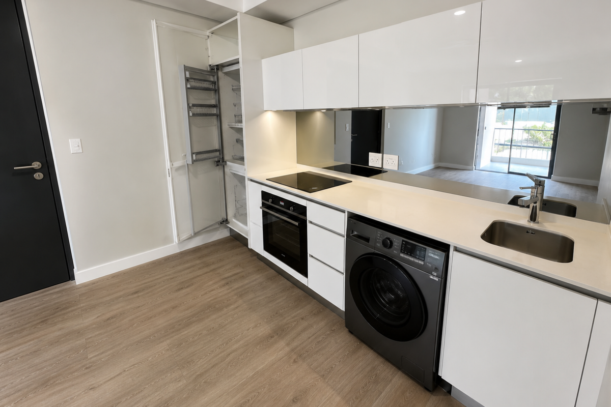 Modern kitchen featuring white gloss cabinetry, integrated pull-out pantry, built-in oven, electric hob, stainless steel sink, and a sleek mirrored splashback.