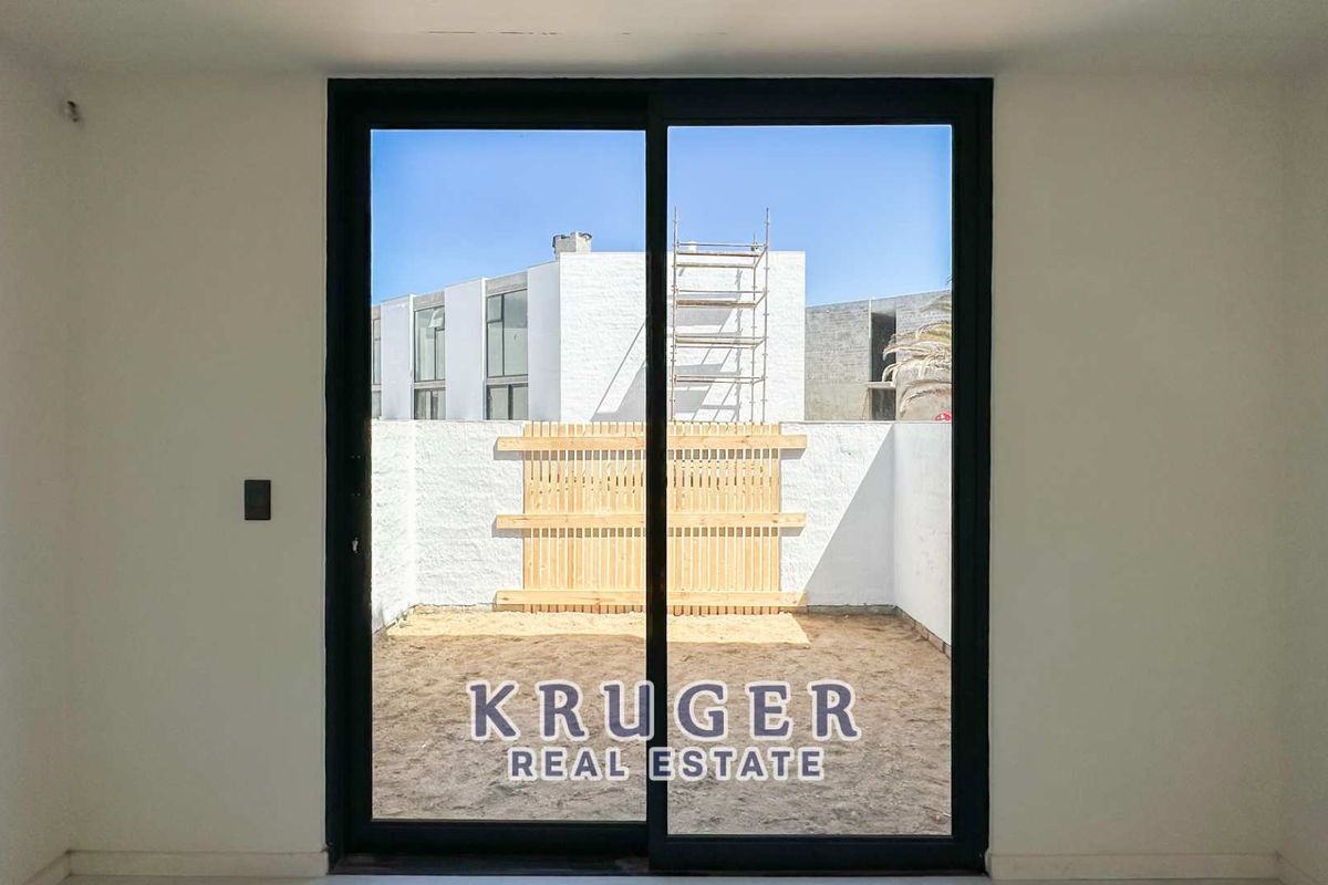 View from an interior room looking out through black-framed sliding glass doors onto a private, enclosed courtyard with a wooden privacy screen.
