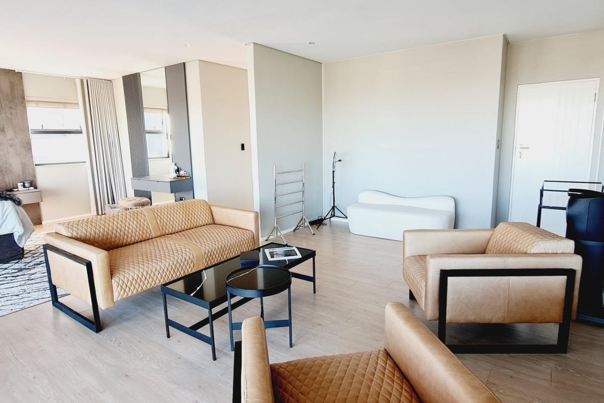 Spacious bedroom suite featuring modern laminate flooring, recessed lighting, and a sophisticated upholstered headboard wall feature with an integrated vanity area.