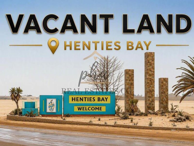 A view of the Henties Bay welcome sign and surrounding vacant land, featuring stone-clad pillars and landscaped garden elements.