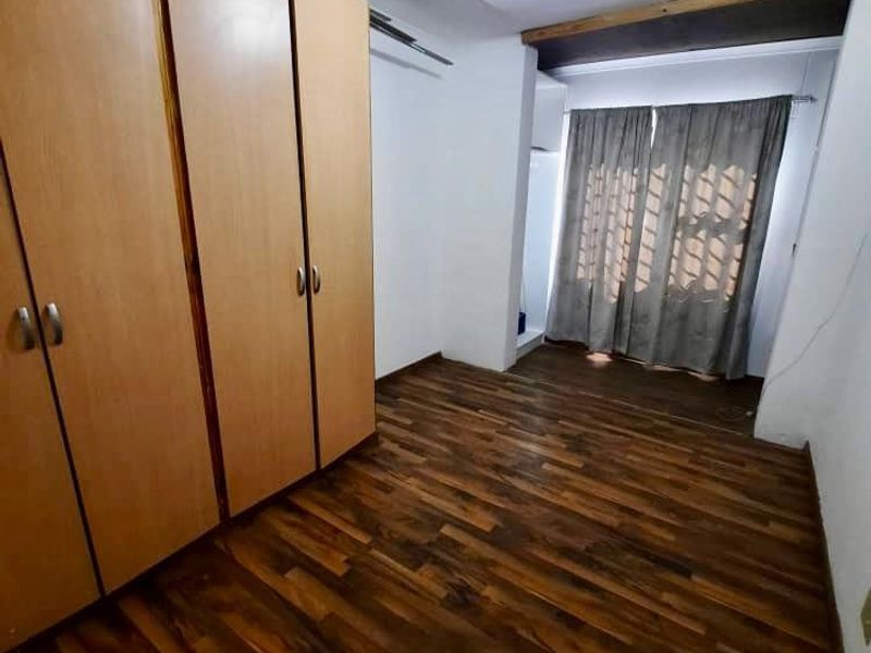 A vacant bedroom featuring laminate flooring and built-in wooden cupboards, offering a neutral space ready for personalization.
