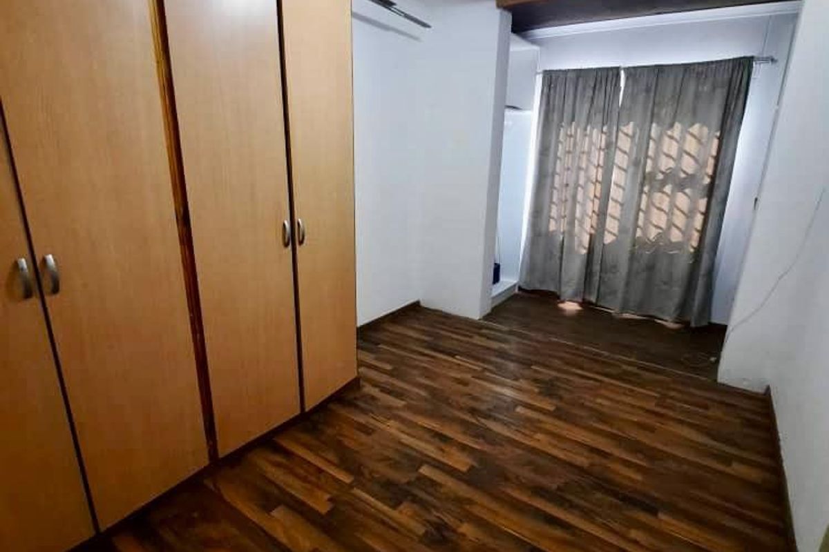 A vacant bedroom featuring laminate flooring and built-in wooden cupboards, offering a neutral space ready for personalization.