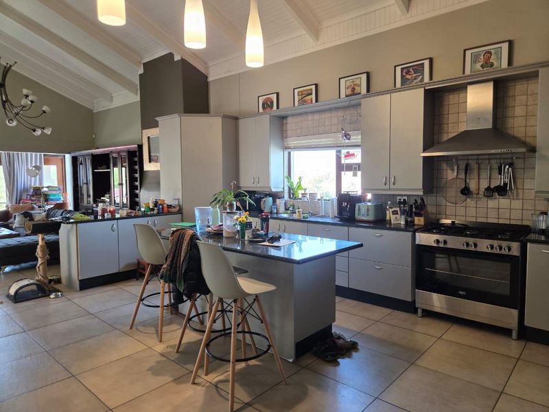 Spacious open-plan kitchen featuring a central island, granite countertops, stainless steel appliances, and vaulted ceilings, seamlessly flowing into the adjacent living area.