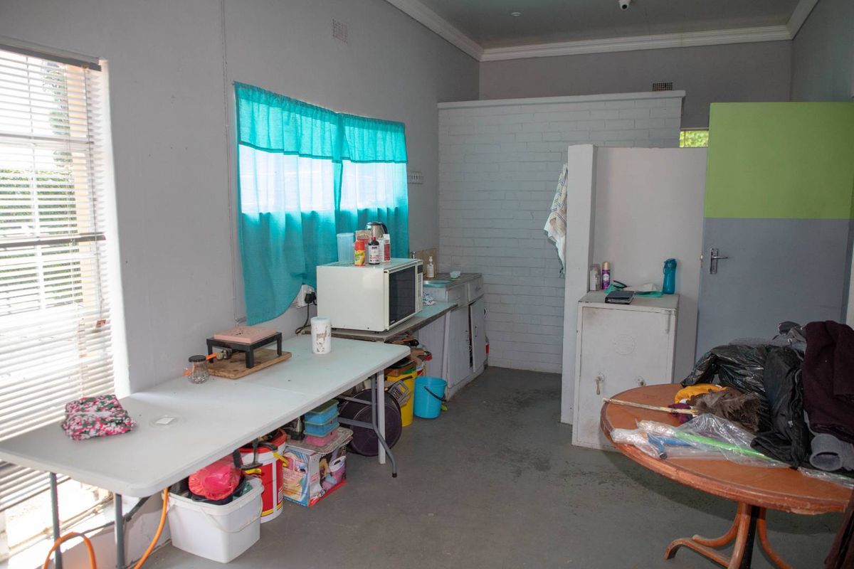A functional utility or kitchenette area featuring basic cabinetry, a sink, and painted brick walls, suitable for renovation or repurposing.