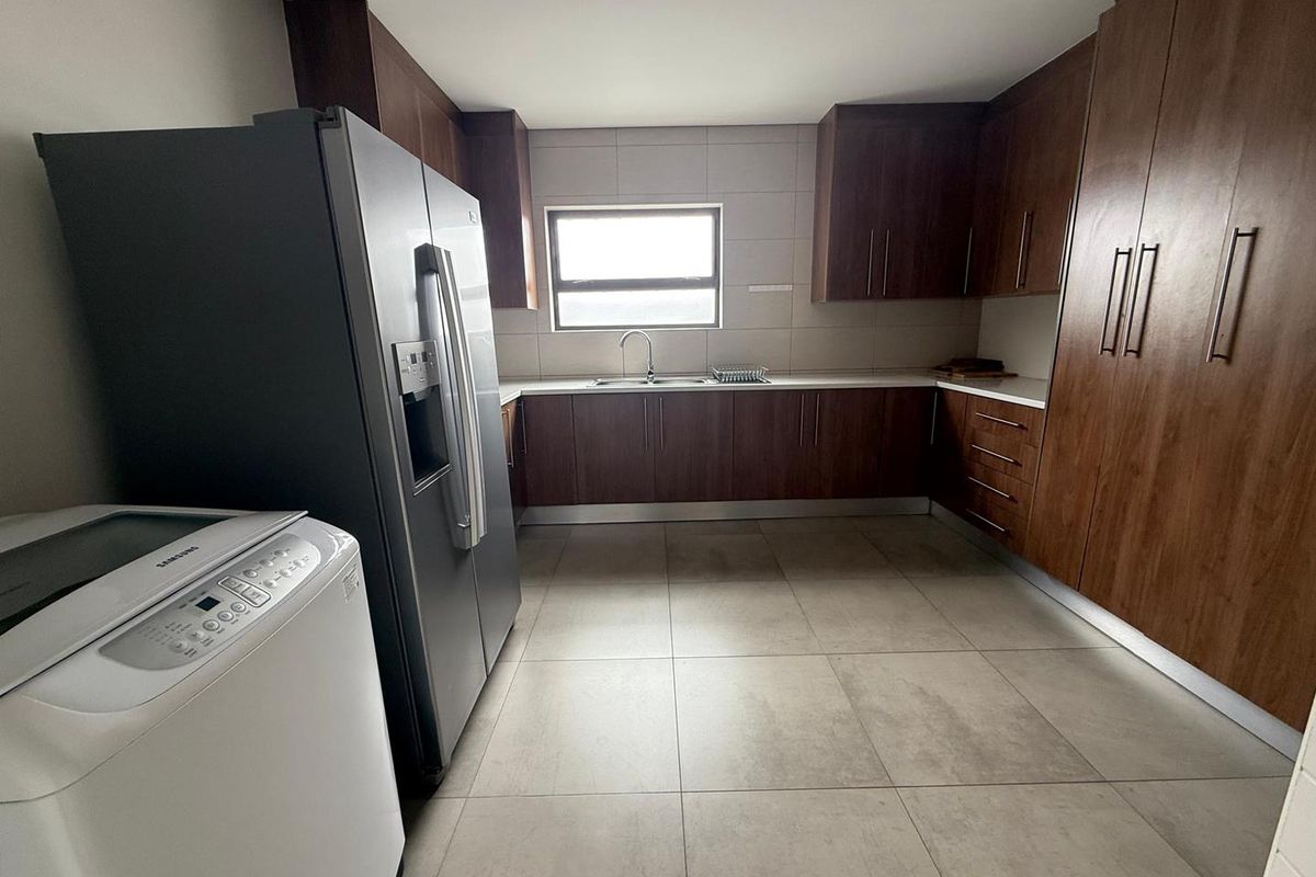 A functional kitchen featuring dark wood cabinetry, tiled flooring, and a stainless steel sink with a window view.