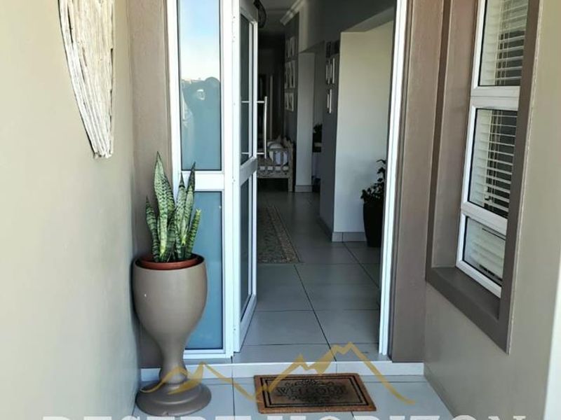 A welcoming entrance area featuring tiled flooring and modern aluminium framed door and window, leading into the main living space.