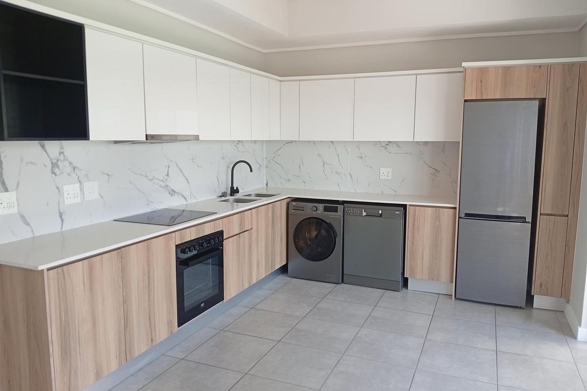 Modern kitchen featuring sleek white and wood-grain cabinetry, marble-look splashback, integrated oven, electric hob, and high-quality tiled flooring.