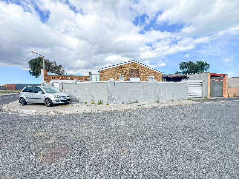 Street view of the property featuring a brick facade and a perimeter boundary wall with gated access.