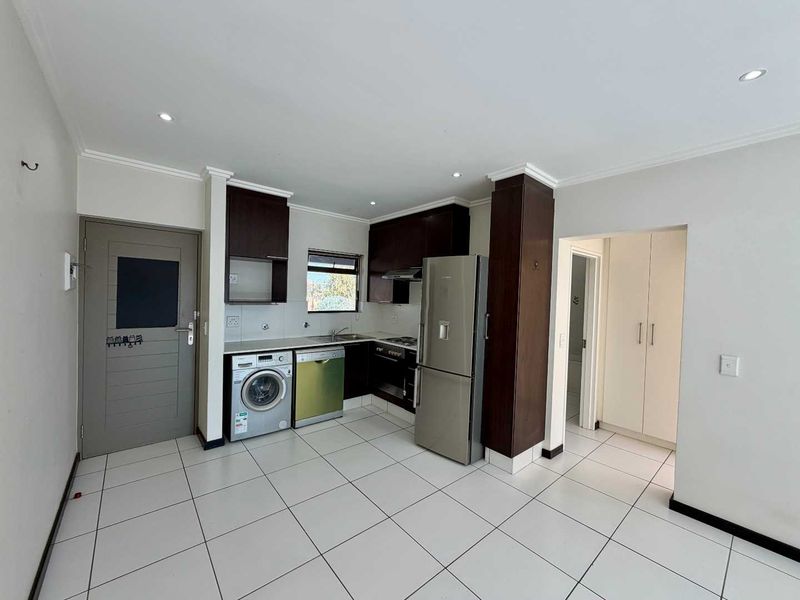 A functional kitchen featuring dark wood cabinetry, tiled flooring, recessed lighting, and integrated appliance spaces, providing a clean and practical cooking area.