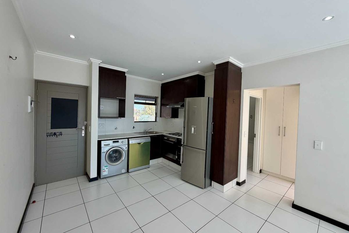 A functional kitchen featuring dark wood cabinetry, tiled flooring, recessed lighting, and integrated appliance spaces, providing a clean and practical cooking area.