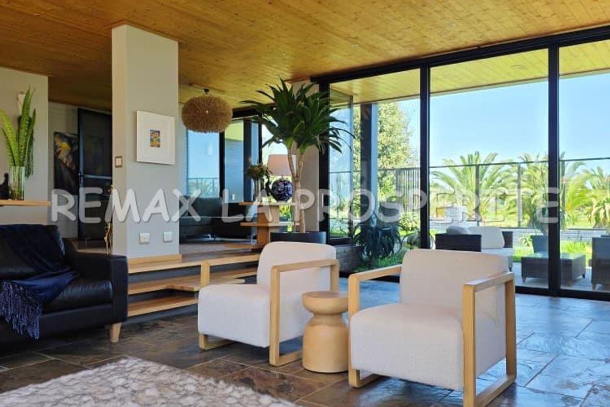 Spacious living area featuring natural stone flooring, a warm timber-clad ceiling, and expansive floor-to-ceiling glass doors opening to the outdoor space.