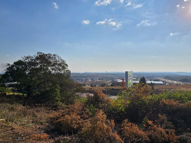 An elevated view overlooking the surrounding landscape and distant urban infrastructure from the vacant residential property.