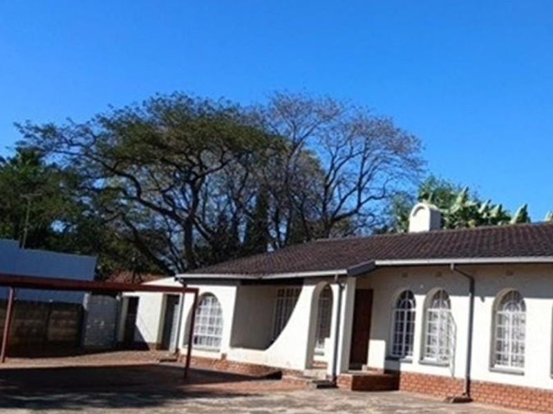 Front exterior view of a single-story residence featuring arched windows, a tiled roof, and an attached carport area.