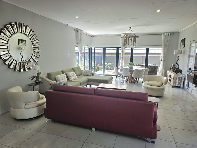 Spacious open-plan living and dining area featuring large sliding glass doors that provide seamless access to the outdoor patio and garden.