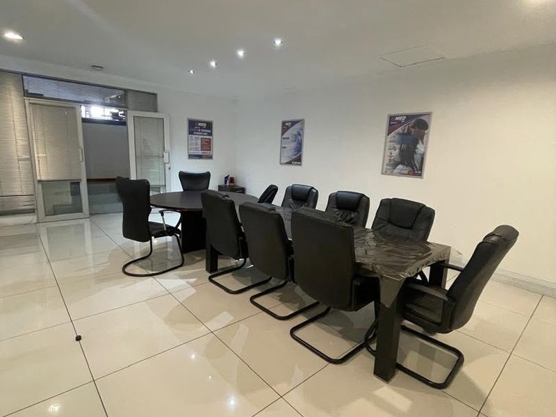 A professional office meeting room featuring polished tiled flooring, recessed downlighting, and a glass partition entrance.
