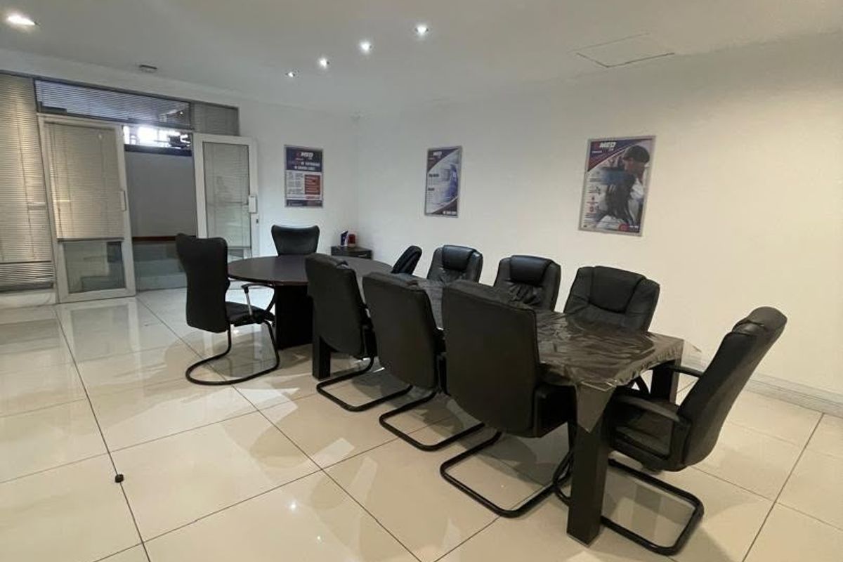 A professional office meeting room featuring polished tiled flooring, recessed downlighting, and a glass partition entrance.