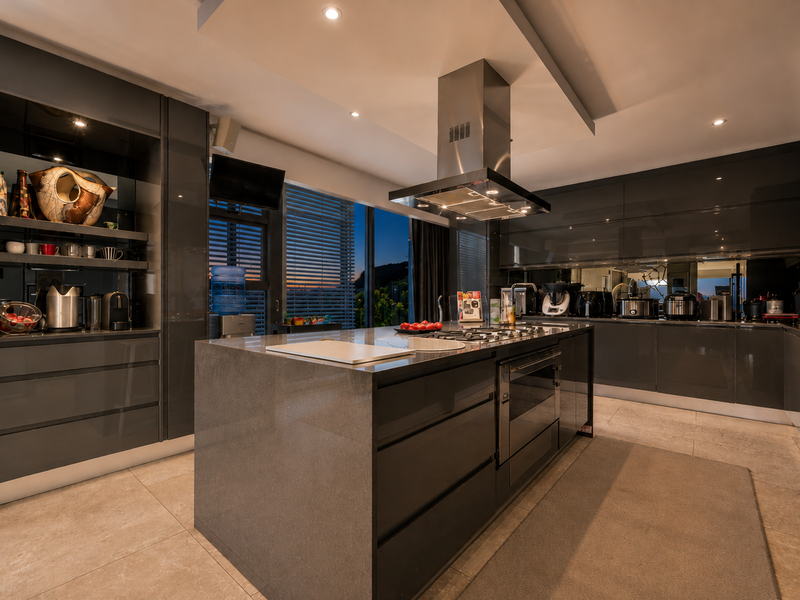 Modern luxury kitchen featuring high-gloss cabinetry, a central island with a gas hob, integrated appliances, and sophisticated recessed lighting.
