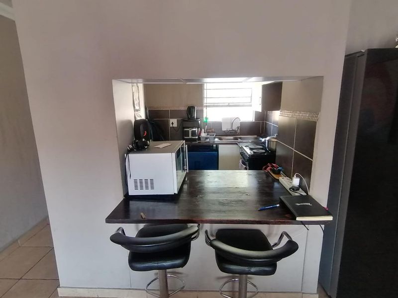 A compact kitchen featuring a breakfast bar pass-through, tiled backsplash, and functional built-in cabinetry with a stove.