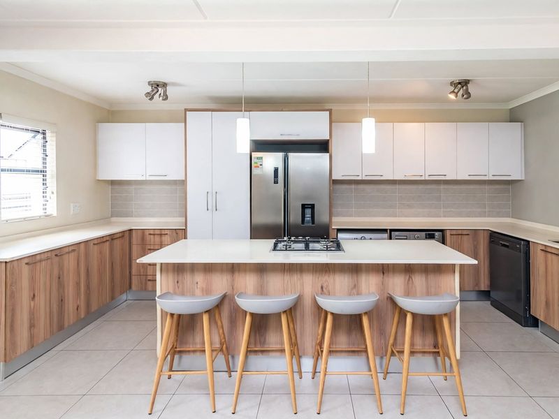Modern kitchen featuring a central island with a gas cooktop, ample built-in cabinetry, integrated appliances, and neutral tiled flooring.