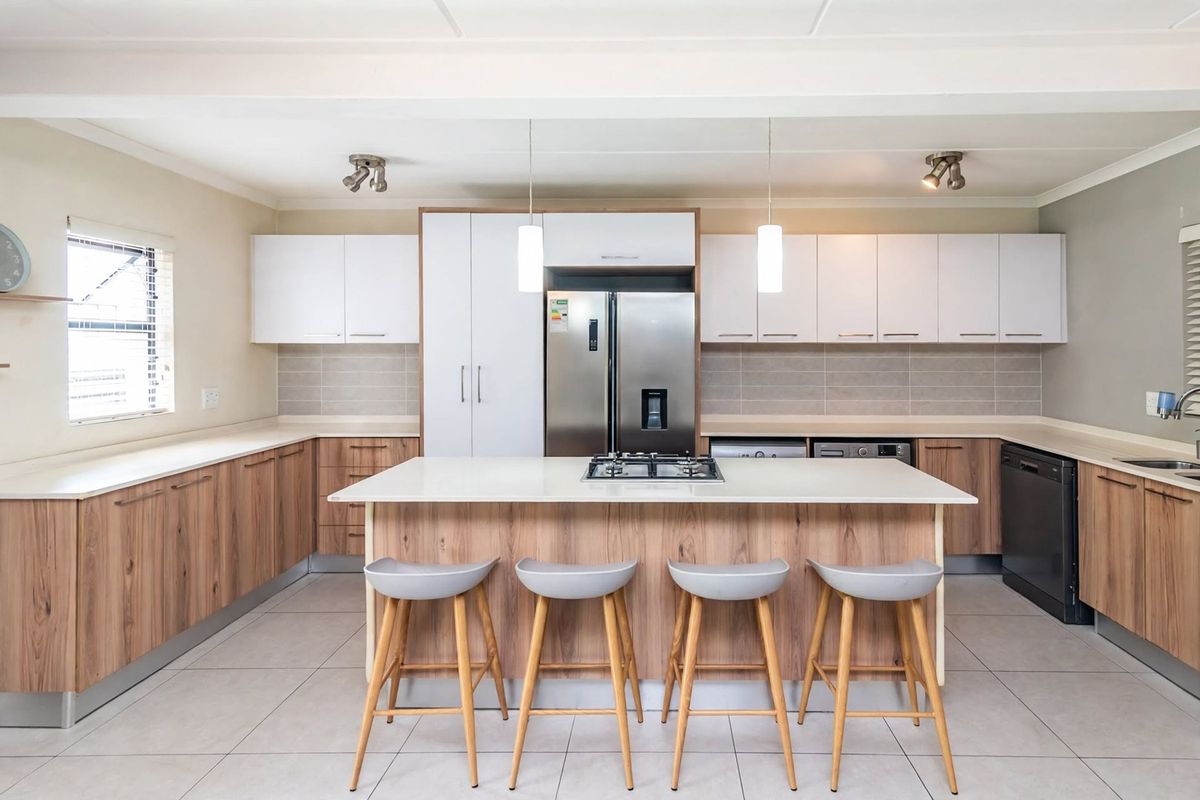 Modern kitchen featuring a central island with a gas cooktop, ample built-in cabinetry, integrated appliances, and neutral tiled flooring.