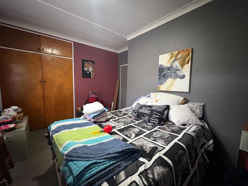 A bedroom featuring built-in wooden cupboards and a neutral color scheme with a feature wall.