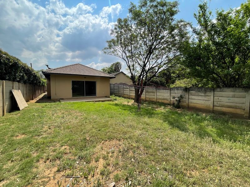 Rear view of the property featuring a private garden, concrete boundary walls, a small patio area, and a sliding door entrance.