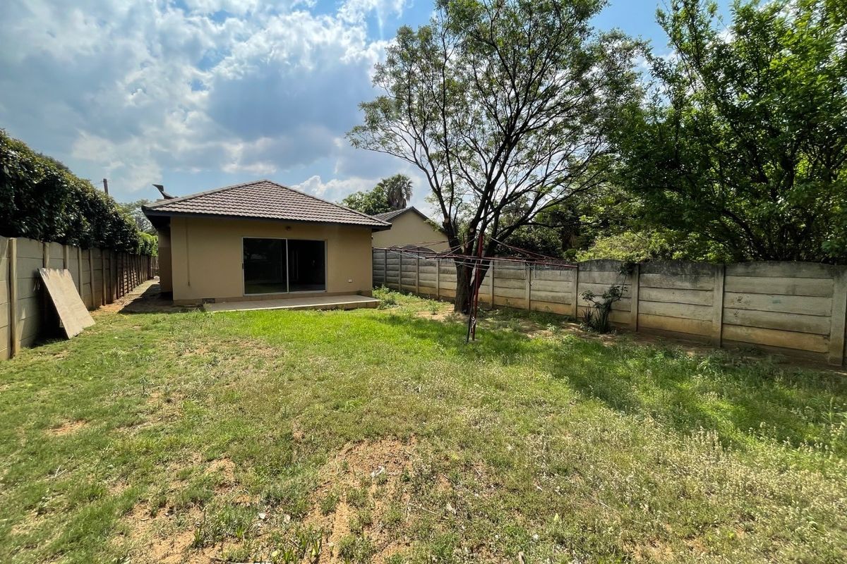 Rear view of the property featuring a private garden, concrete boundary walls, a small patio area, and a sliding door entrance.