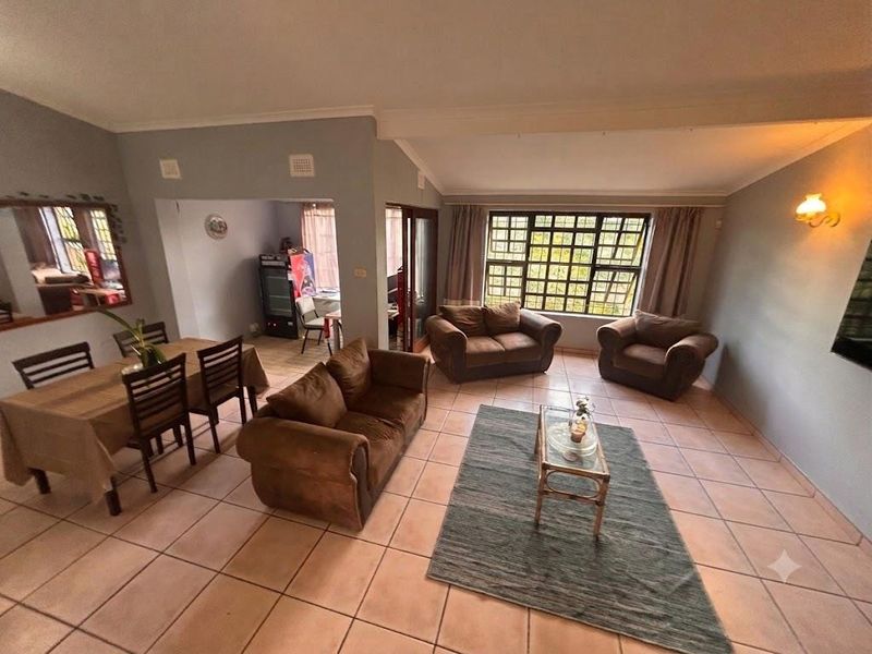 Spacious open-plan living and dining area featuring tiled flooring, large grid-pattern windows, and neutral wall tones, offering a versatile layout for family living.