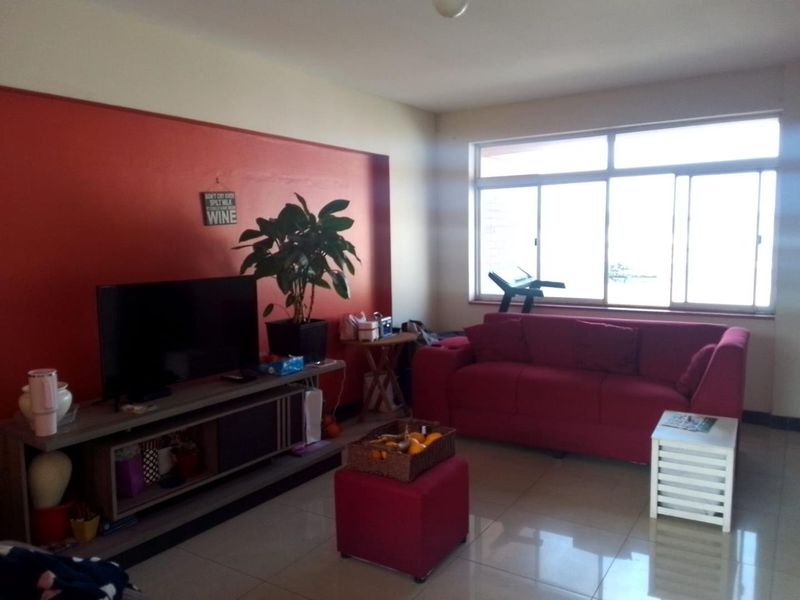 A living room featuring tiled flooring and a large sliding window that provides natural light.