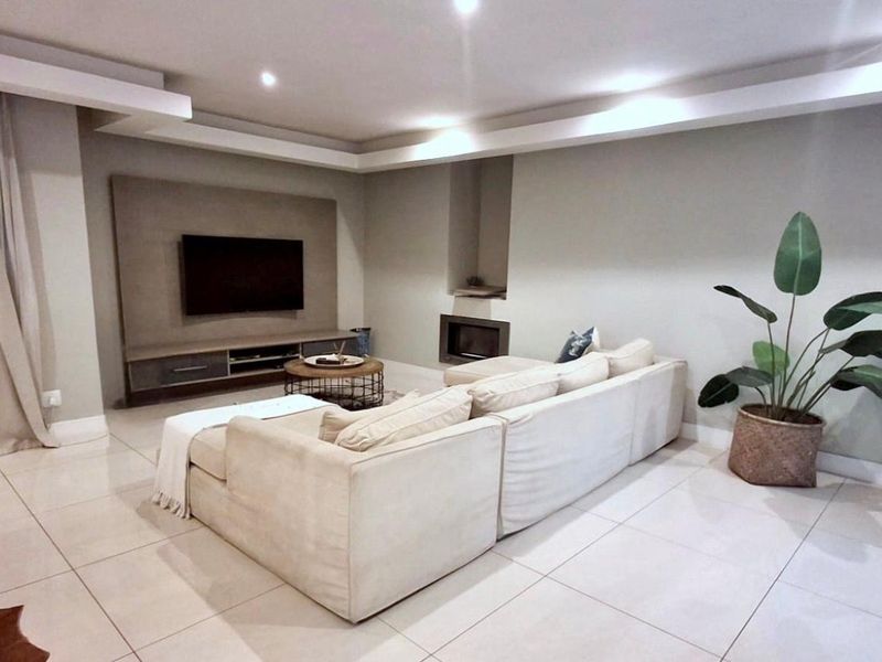 A modern living room featuring tiled flooring, recessed ceiling lighting, a built-in fireplace, and a custom media wall unit.