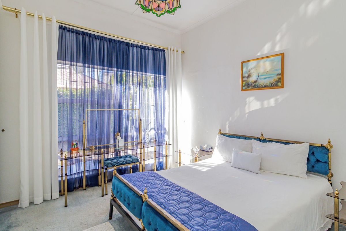 A well-lit bedroom featuring built-in wardrobes, carpeted flooring, and large windows with curtain tracks, offering a comfortable and functional living space.