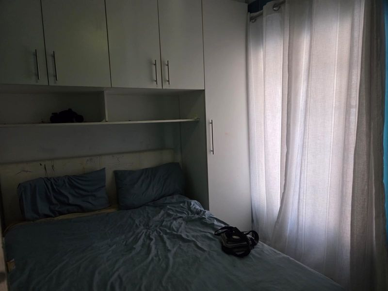A bedroom featuring built-in cupboards and overhead storage units, providing functional storage space.