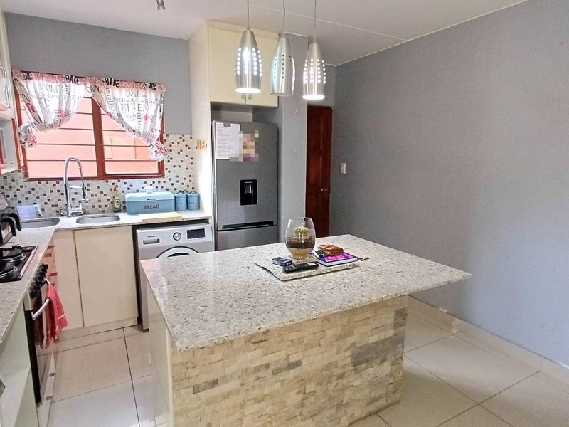 A functional kitchen featuring a central island with granite countertop, tiled backsplash, built-in oven, and tiled flooring throughout.
