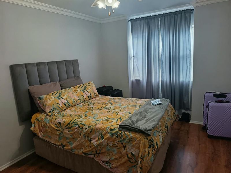 A well-maintained bedroom featuring laminate flooring, crown molding, and a ceiling fan, providing a comfortable and neutral living space.
