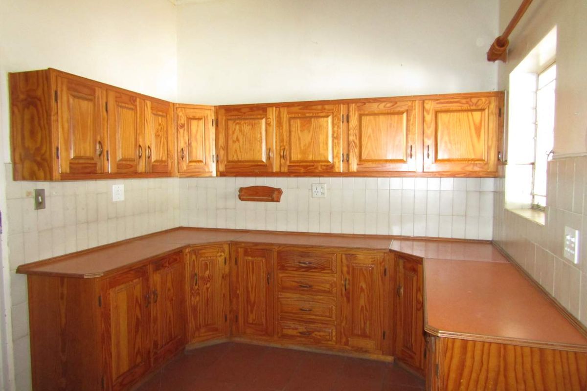 A dated kitchen featuring traditional wooden cabinetry, laminate countertops, and tiled backsplash, offering a blank canvas for modern renovation and design updates.