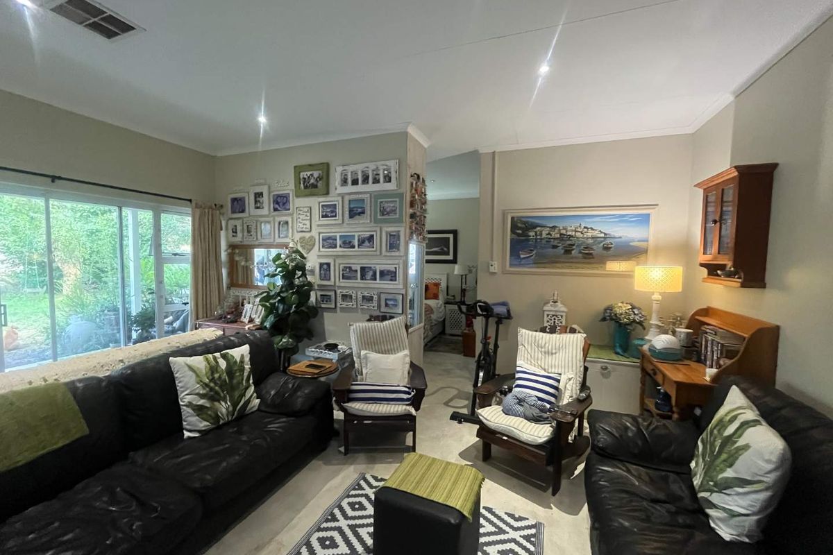A comfortable living room featuring recessed downlighting, large sliding glass doors providing garden access, and neutral wall finishes.