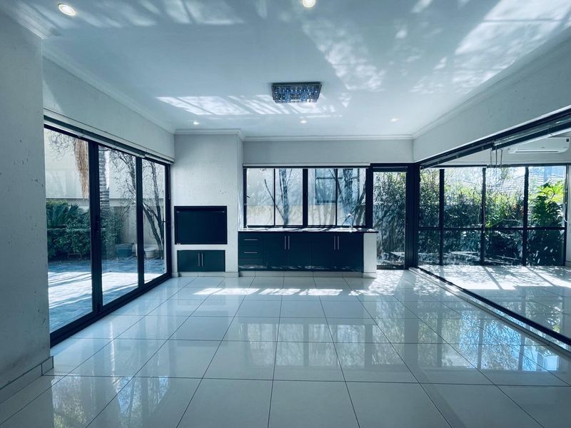 Spacious, light-filled living area featuring large sliding glass doors, polished tile flooring, built-in cabinetry, and a fireplace, offering seamless indoor-outdoor flow.
