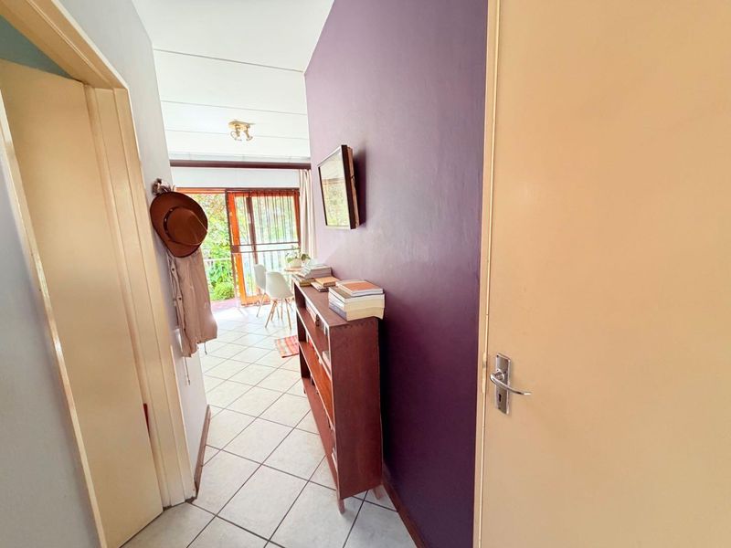 A functional hallway featuring tiled flooring and access to an adjoining living space with natural light.