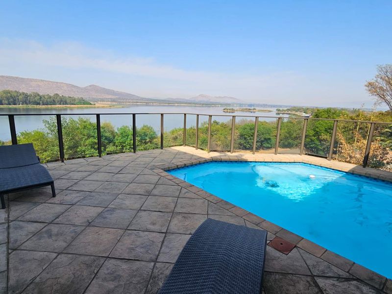 Outdoor pool area featuring a paved patio, glass balustrade, and expansive views of the lake and surrounding mountains.