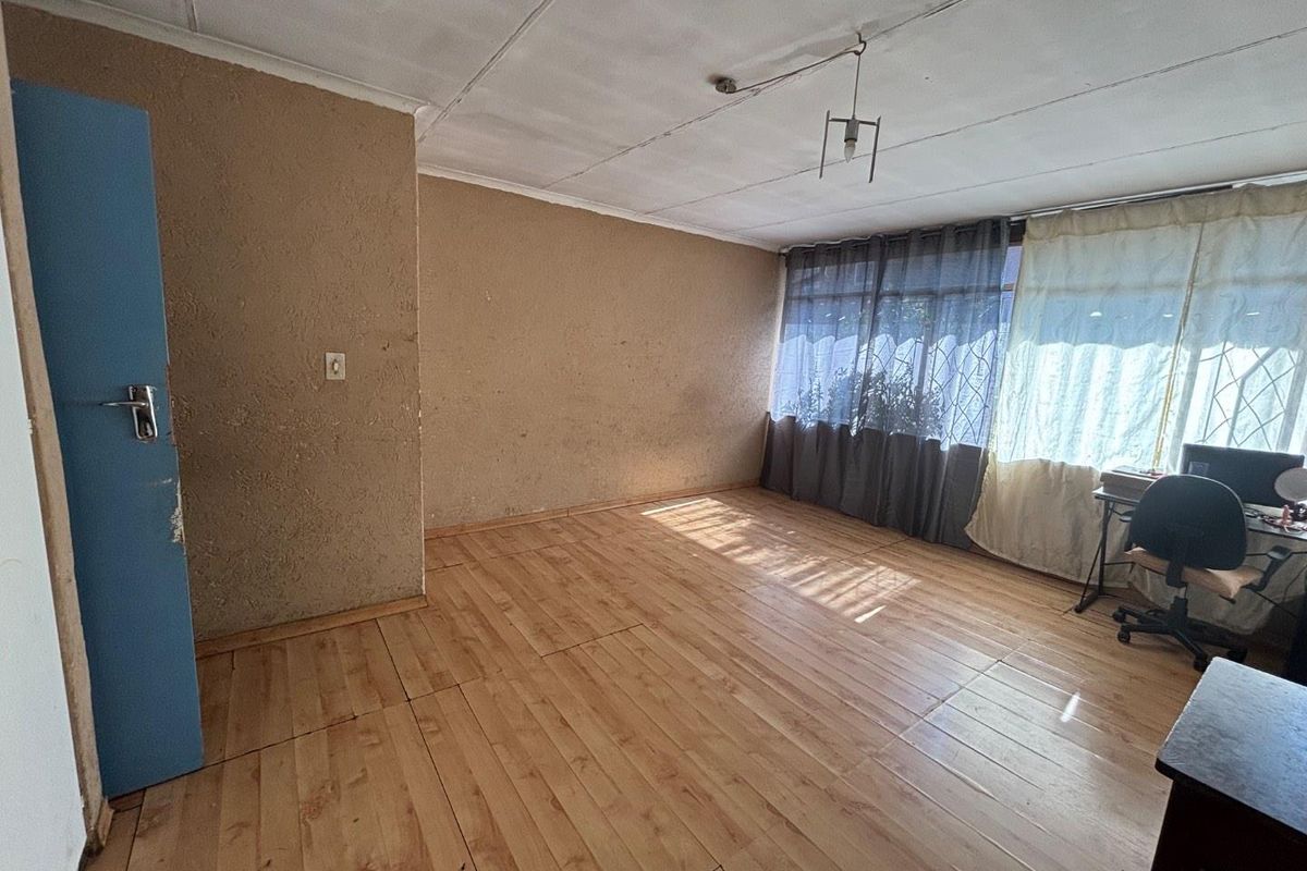 A spacious living area featuring laminate flooring and textured walls, offering a blank canvas for renovation and interior design updates.