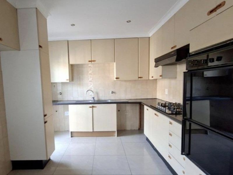 A functional kitchen featuring built-in cabinetry, a gas hob, an integrated oven, and tiled flooring, offering a clean canvas for potential cosmetic updates.