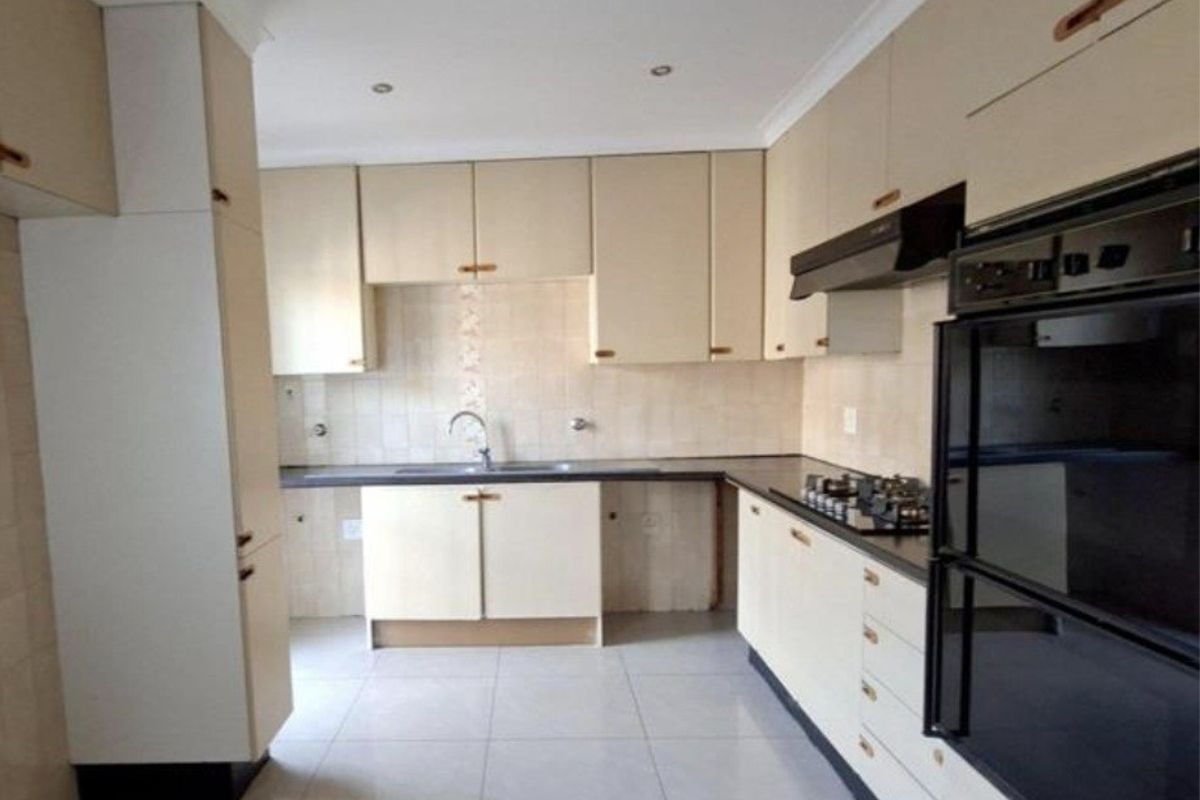 A functional kitchen featuring built-in cabinetry, a gas hob, an integrated oven, and tiled flooring, offering a clean canvas for potential cosmetic updates.