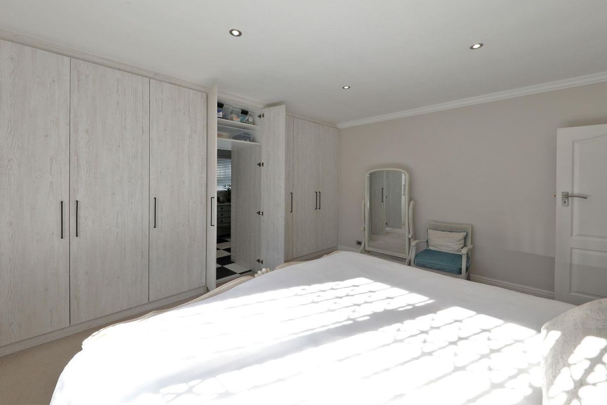 Spacious bedroom featuring extensive built-in cabinetry with a light wood-grain finish, recessed ceiling lighting, and neutral wall tones.