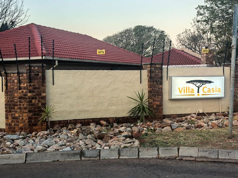 Exterior view of the property boundary wall featuring electric fencing, a tiled roof, and the Villa Casia signage.