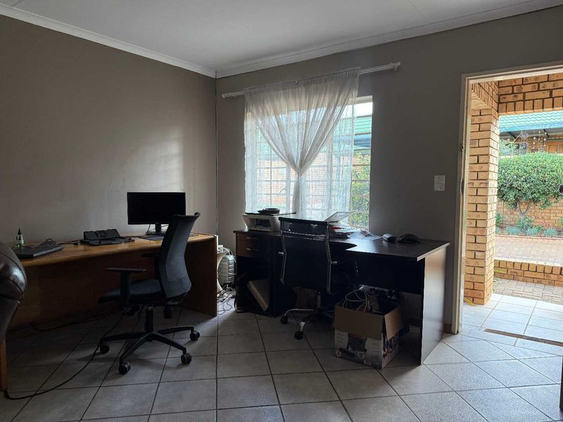 A functional home office space featuring tiled flooring and direct access to an outdoor patio area.