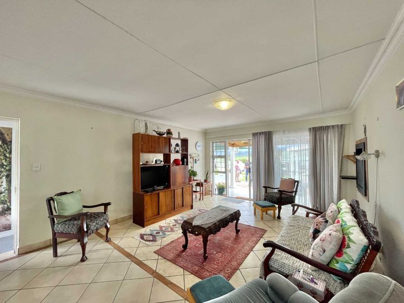 Spacious living room featuring tiled flooring, coved ceilings, and large sliding glass doors providing natural light and access to the outdoor patio area.