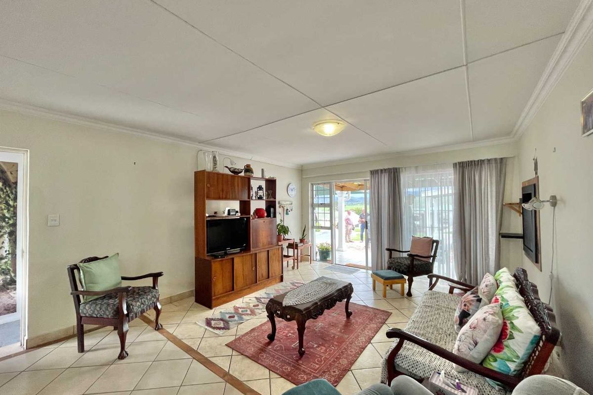 Spacious living room featuring tiled flooring, coved ceilings, and large sliding glass doors providing natural light and access to the outdoor patio area.