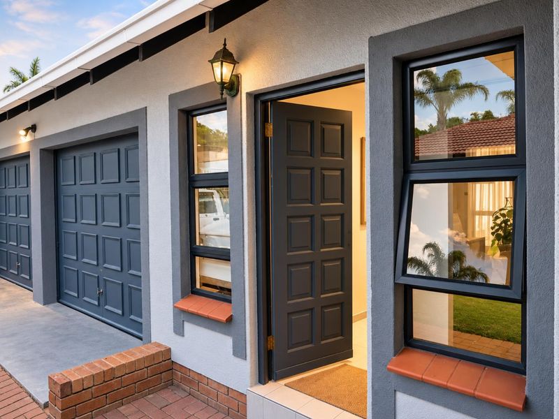 Well-maintained front exterior featuring a double garage, modern panelled front door, and dark aluminium window frames with brick detailing.