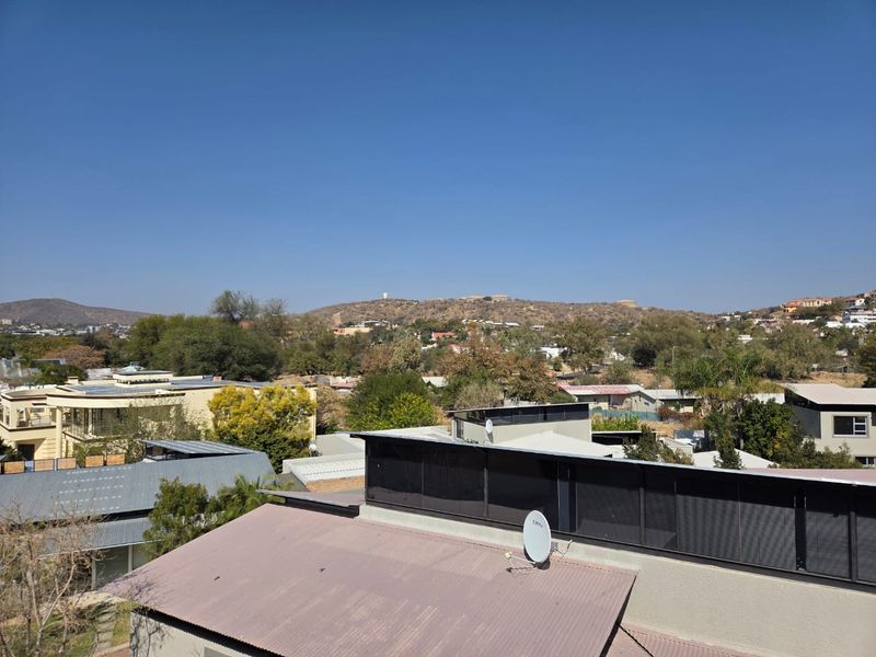 An elevated view overlooking the surrounding neighborhood and distant hills, showcasing the local landscape and residential rooftops.