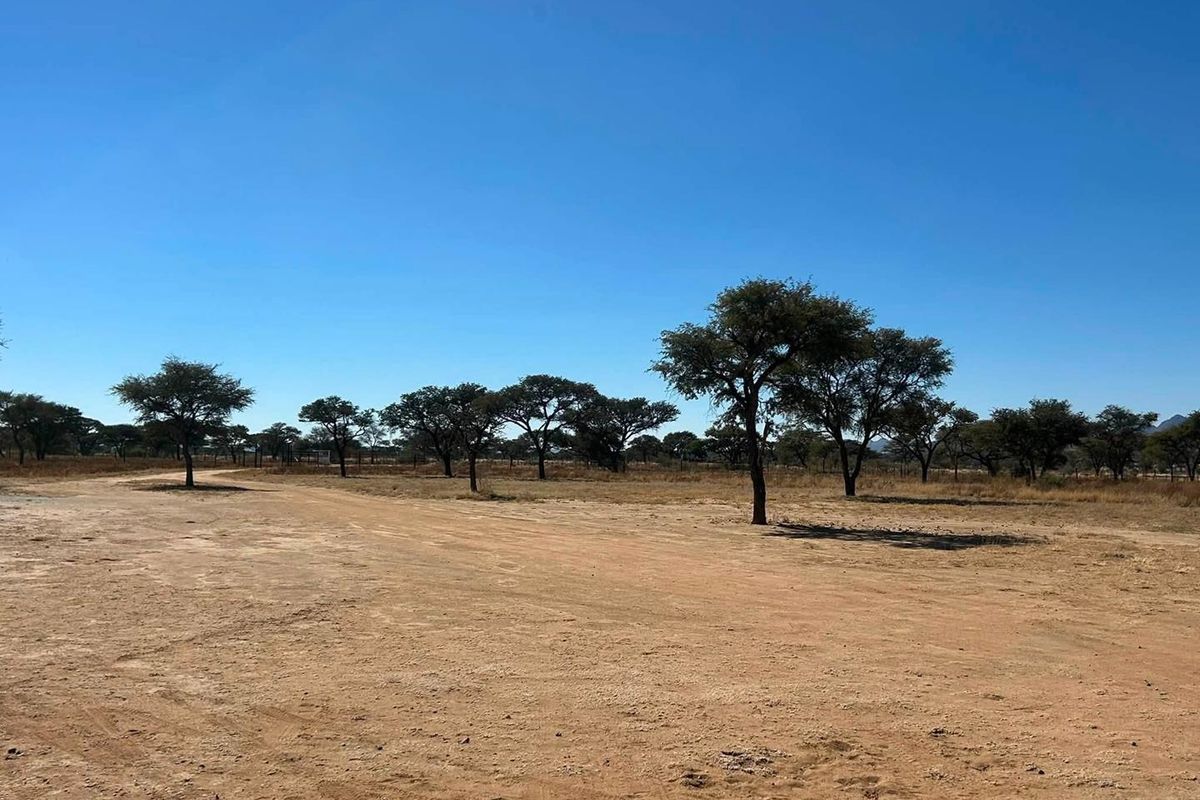 An expansive, open plot of land featuring natural vegetation, scattered indigenous trees, and clear blue skies, suitable for development or agricultural use.